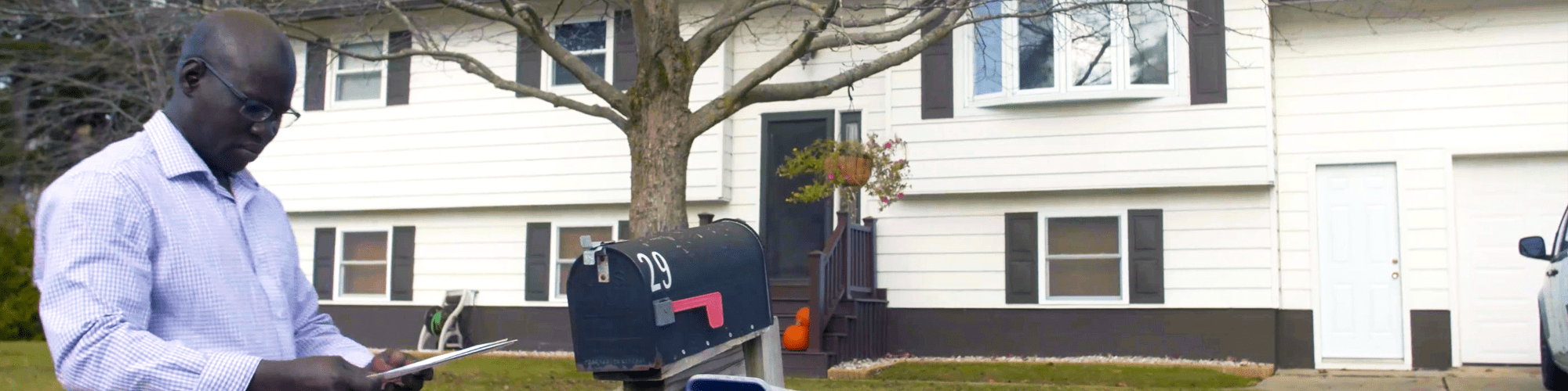 A man in front of his home, checking his mail at the mailbox