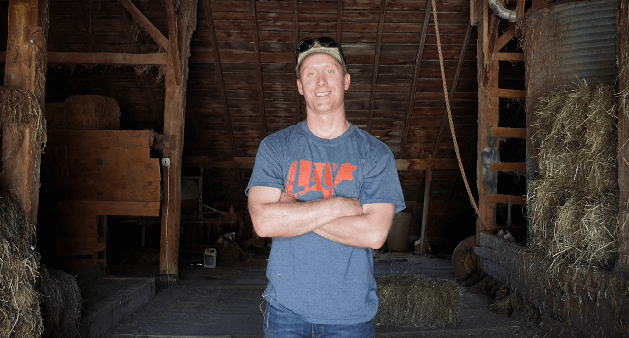 Man standing with arms crossed inside a barn.
